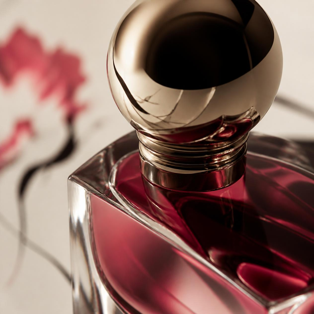 Close view of the bottle, crimson glass and a polished gold cap